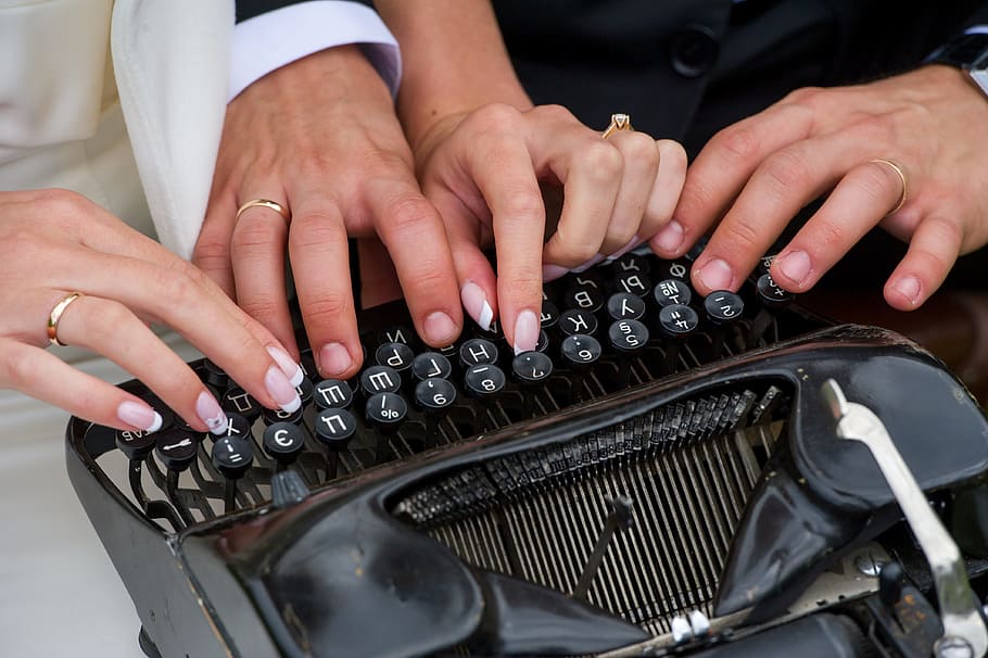 closeup photography of two person holding black typewriter HD wallpaper