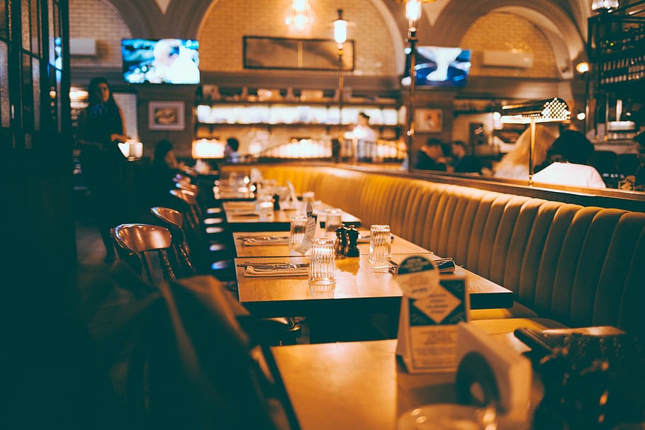 depth photography of empty table inside restaurant, brown wooden dining sets beside standing woman in restaurant HD wallpaper