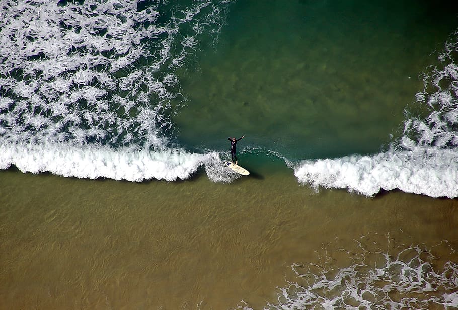 aerial photo of person surfing on beach during daytime, surfer