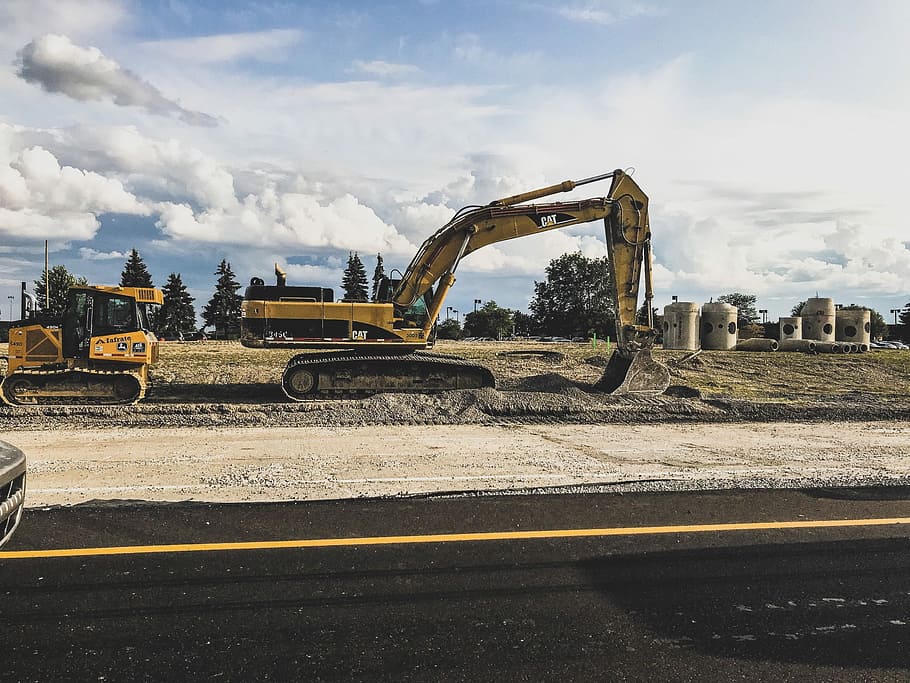 yellow excavator, cat, digger, dirt, mud, silo, road, sky, clouds HD wallpaper