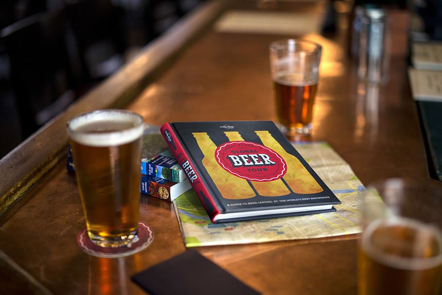 clear drinking glass beside Beer book, two clear glass cups beside book HD wallpaper