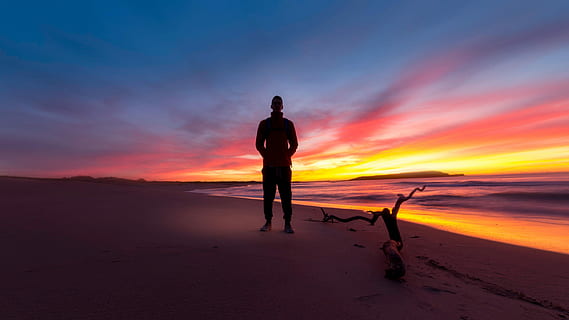 silhouette of man standing at seashore during golden hour, sunset HD wallpaper