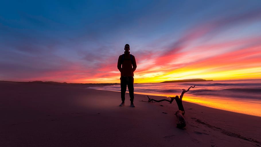 silhouette of man standing at seashore during golden hour, sunset HD wallpaper