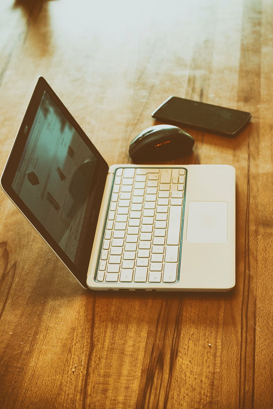 black smartphone beside black and silver laptop computer on brown wooden surface HD wallpaper