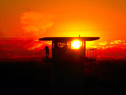silhouette of person standing on tower house during golden hour HD wallpaper