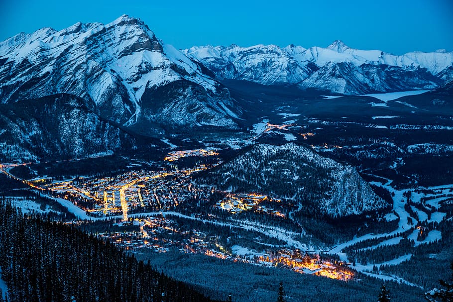 landscape photography of mountain, aerial photography of lighted buildings near mountain covered with snow HD wallpaper