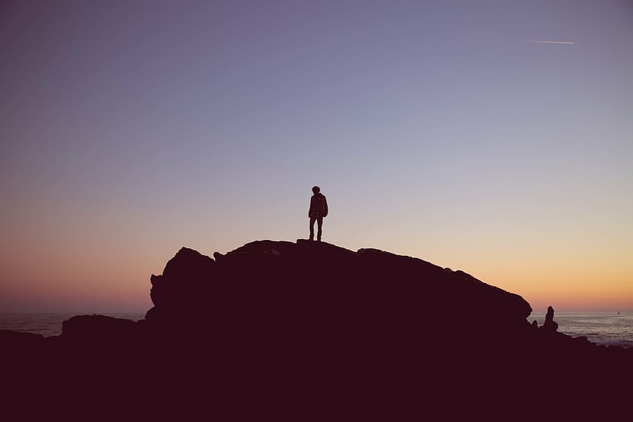 man standing in boulder near body of water, beach, dawn, dusk HD wallpaper