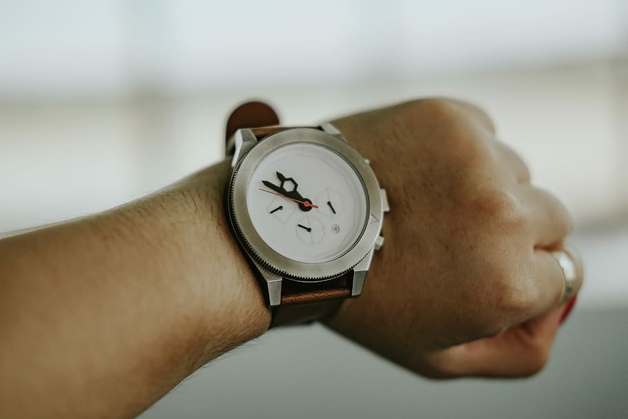 person wearing chronograph watch at 10:50, round silver-colored analog watch displaying 11:50 HD wallpaper