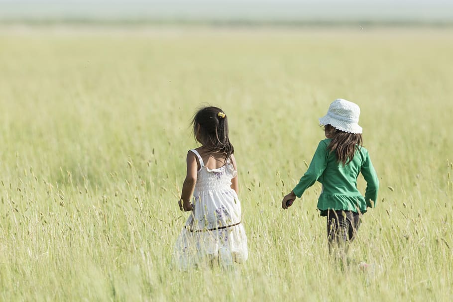 two girls walking on grass field during daytime, good friends