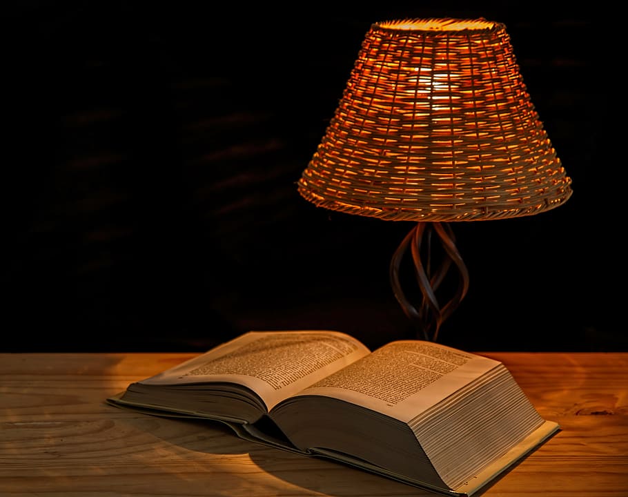 opened book on table near turned on table lamp, light, bedside lamp