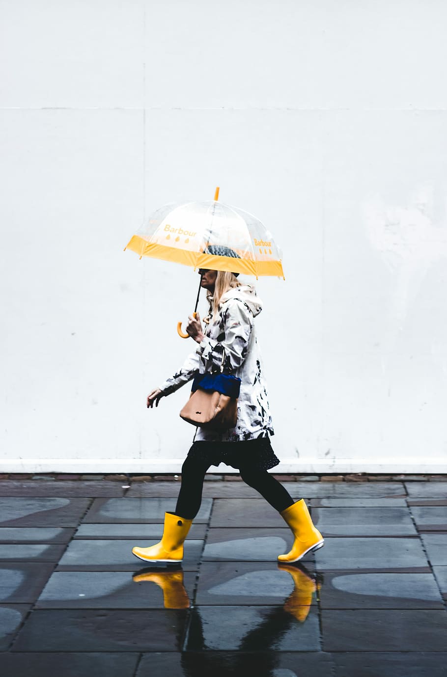 woman walking while holding opened yellow umbrella, person walking on sidewalk holding umbrella during day time HD wallpaper