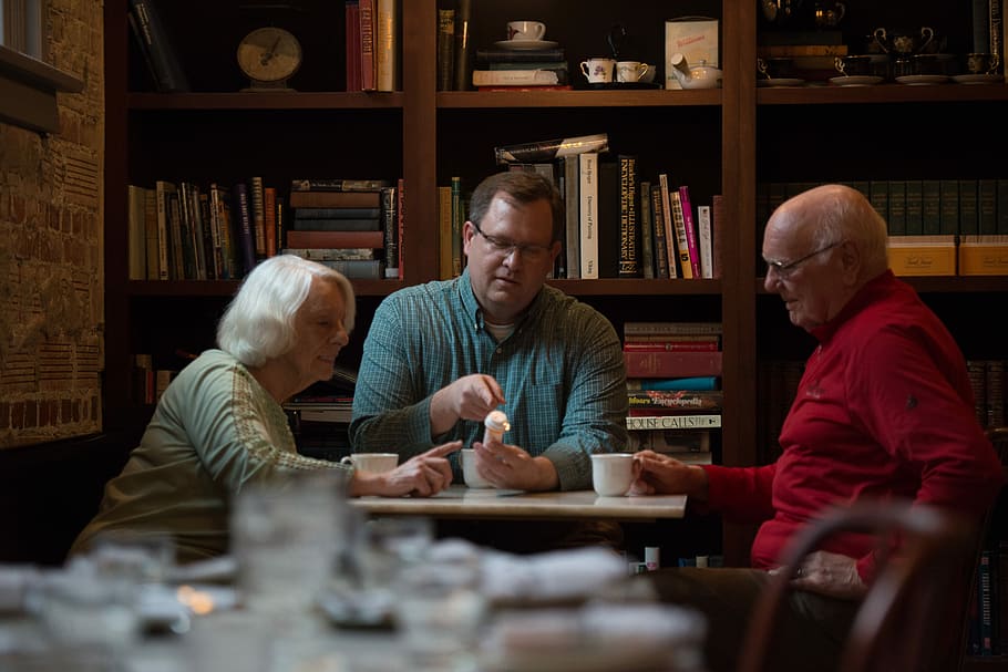 Kevin Bacon with seniors, three person in front of white wooden table inside room