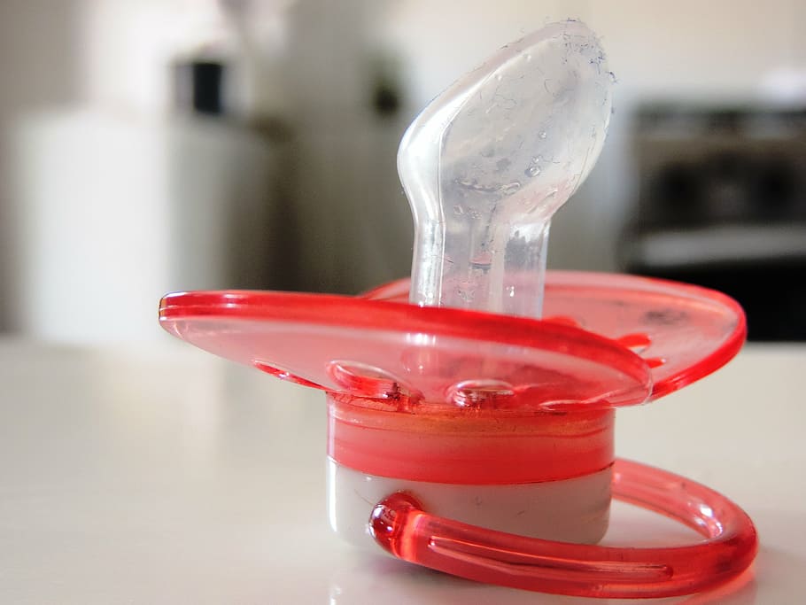 red and white pacifier on white surface selective focus photography HD wallpaper