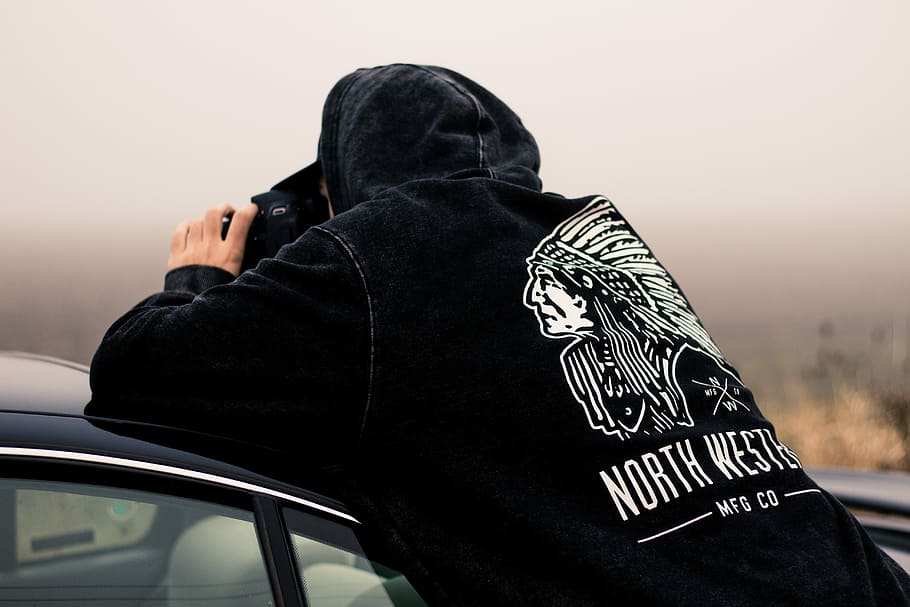 man holding DSLR camera, man leaning on car hood while taking picture HD wallpaper