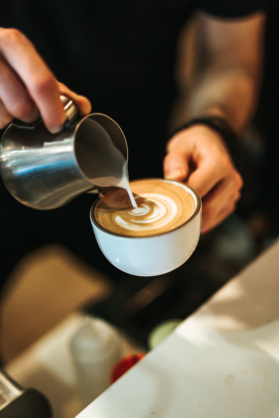 person preparing latte with art, person pouring milk on white ceramic mug HD wallpaper