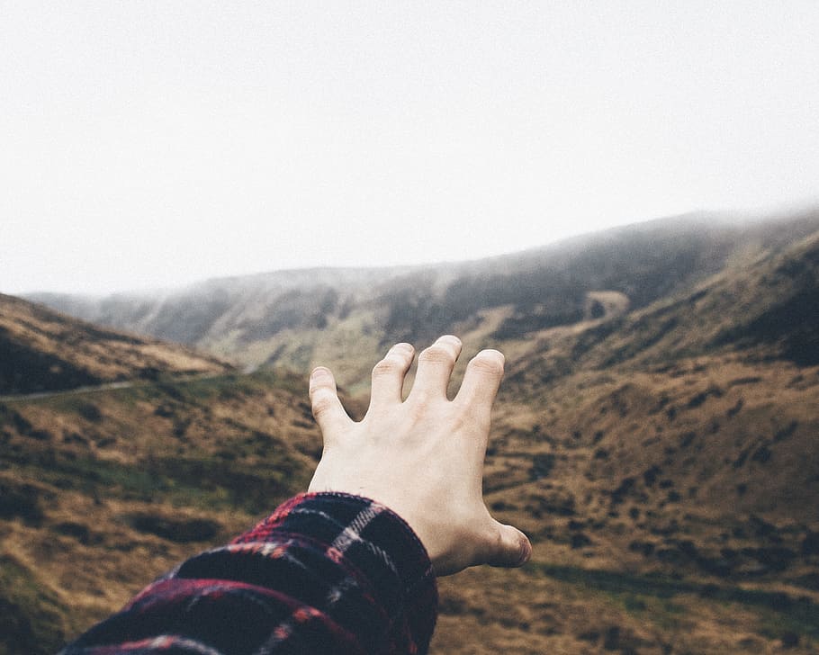 point of view photography of person raising hand towards mountains, person reaching the mountains HD wallpaper