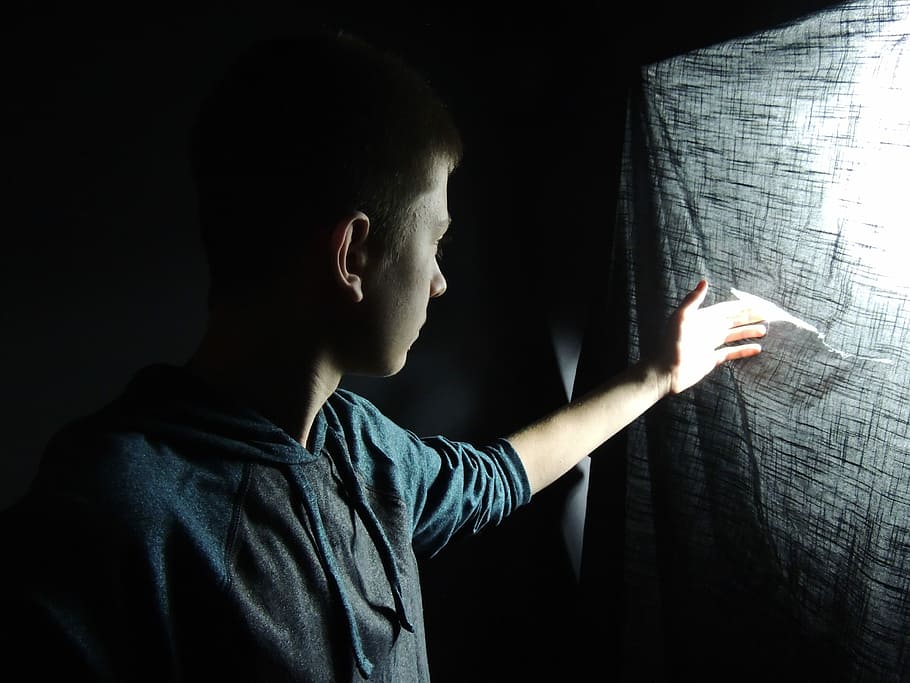man touching gray textile with light behind, man wearing pullover top peeking inside dark room HD wallpaper