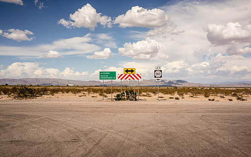 green signage on concrete road during day time, landscape photography of four street signs under blue sky HD wallpaper
