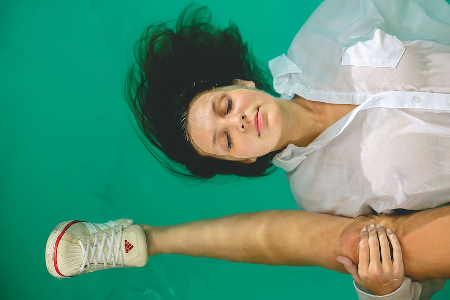 Day Dream, woman in white shirt floating on water while holding human leg