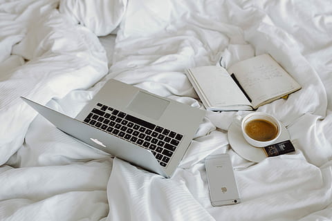 Woman working on a laptop while enjoying a breakfast coffee and chocolate in bed HD wallpaper