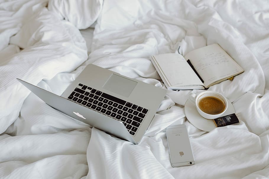 Woman working on a laptop while enjoying a breakfast coffee and chocolate in bed HD wallpaper