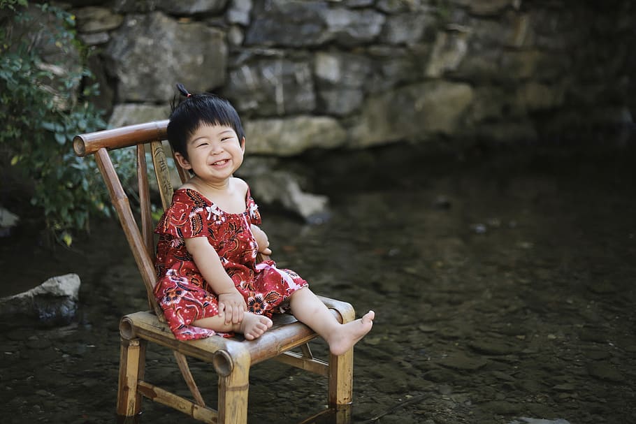 toddler sitting on brown wooden chair, girl sitting on brown wooden chair while smiling HD wallpaper