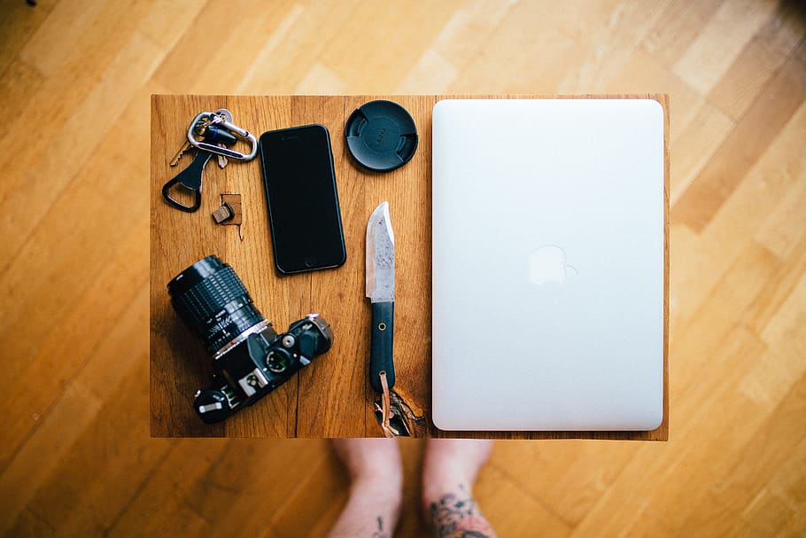black android smartphone and silver MacBook, flat lay photography of black DSLR camera, black smartphone, and black knife