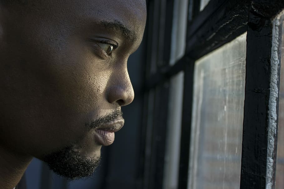 man near glass window pane, man staring out a window, face, african american
