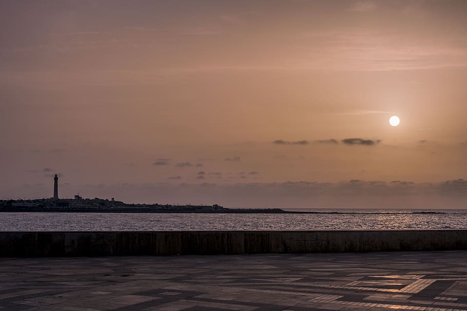 sun, sunset, calm, ocean, sky, lighthouse, side, water, sea HD wallpaper