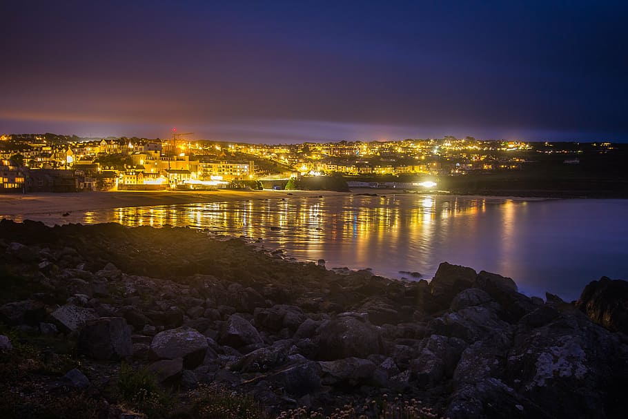 photo of city near body of water during nightime, st ives, ocean