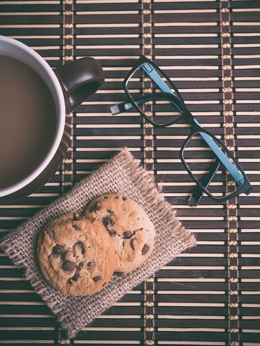 black framed eyeglasses beside two cookies and ceramic mug with coffee on table HD wallpaper