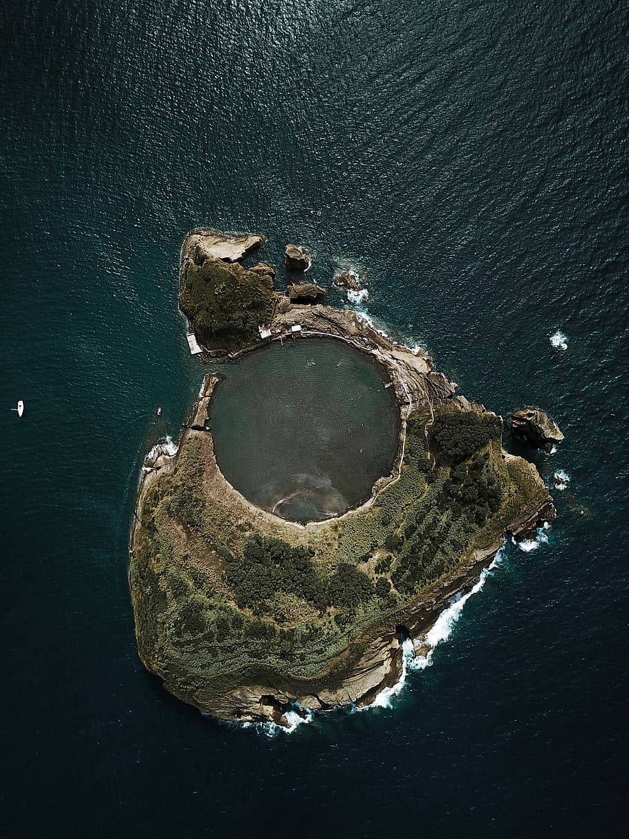 top view photography of island covered with trees surrounded by body of water during daytime, bird's eyeview of island