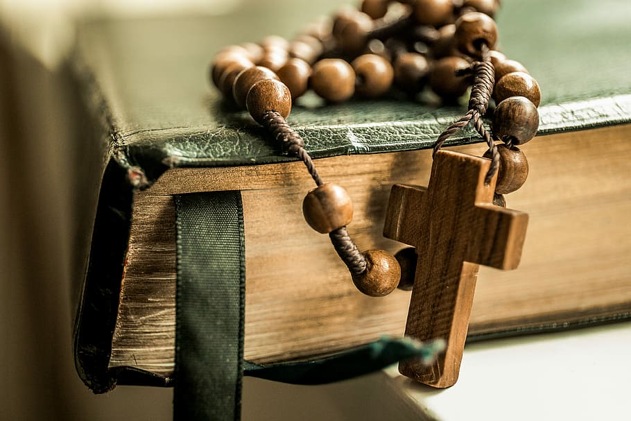 brown tesbih prayer beads on black book, shallow focus photography of brown rosary on book