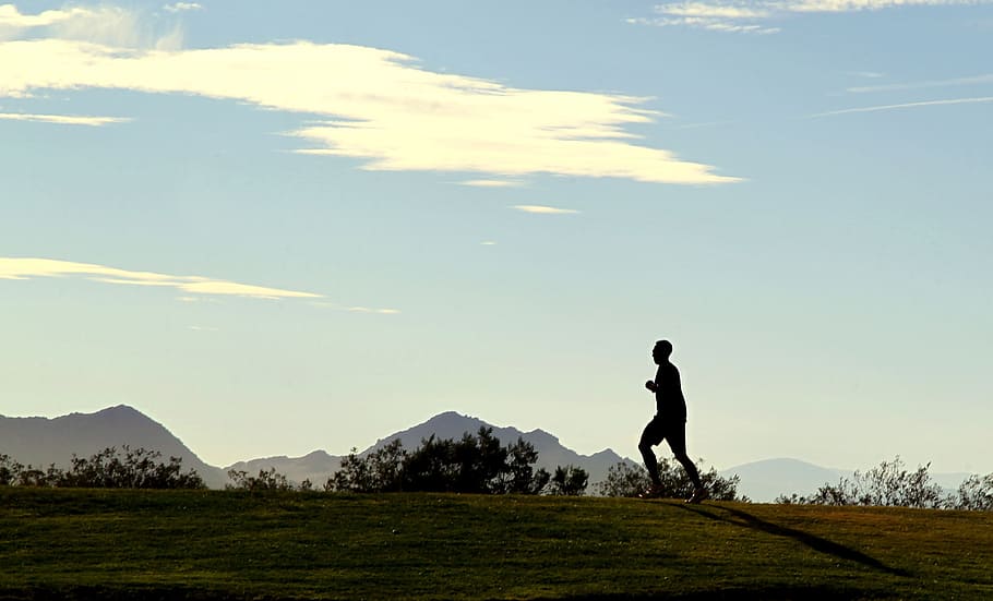 silhouette of man running on top of hill under white clouds at daytime HD wallpaper