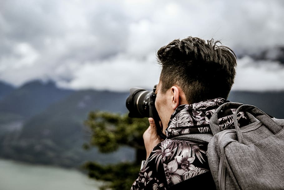 person taking picture of mountain and trees at daytime, person using camera with backpack HD wallpaper
