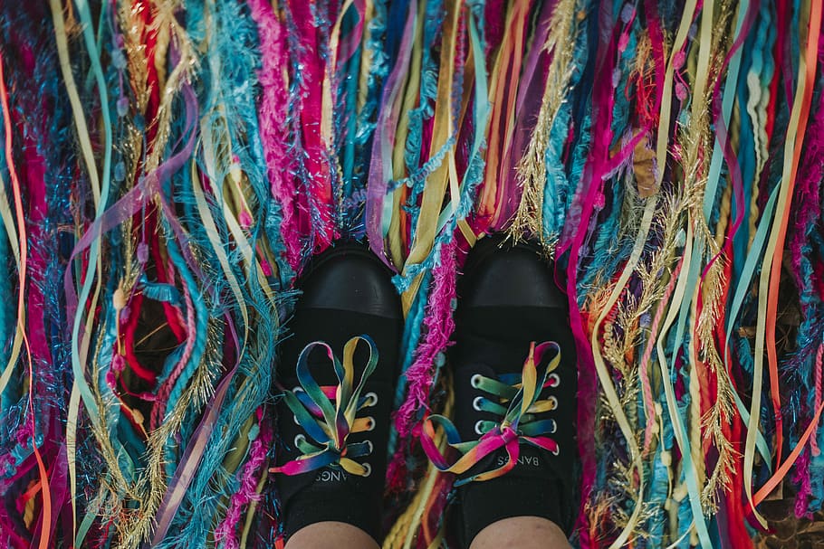 person wearing pair of black low-top sneakers standing on multicolored straps, person showing pair of black sneakers on multicolored strings HD wallpaper