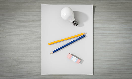 two yellow and blue pencils between LED bulb and eraser on white surface HD wallpaper