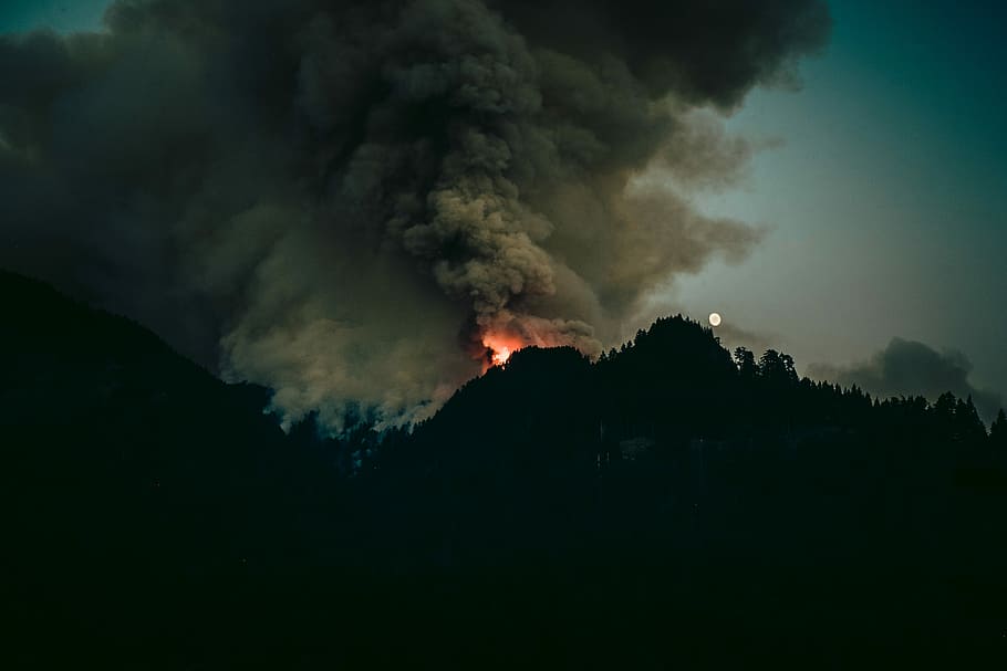 forest fire at daytime, silhouette of mountain with fire on top