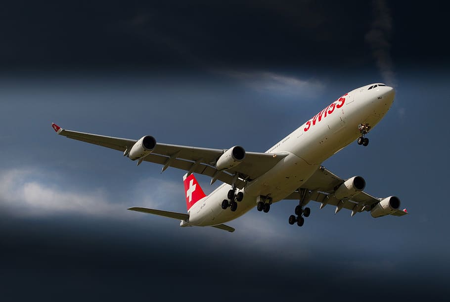 white and red airbus flying under cloudy blue sky during daytime
