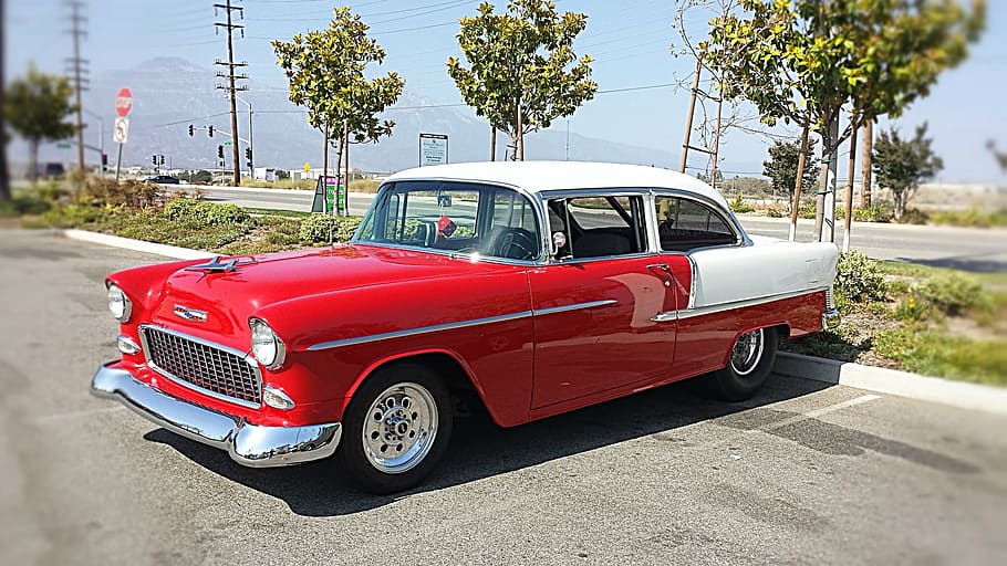 classic red and white coupe park near green leaf tree, retro