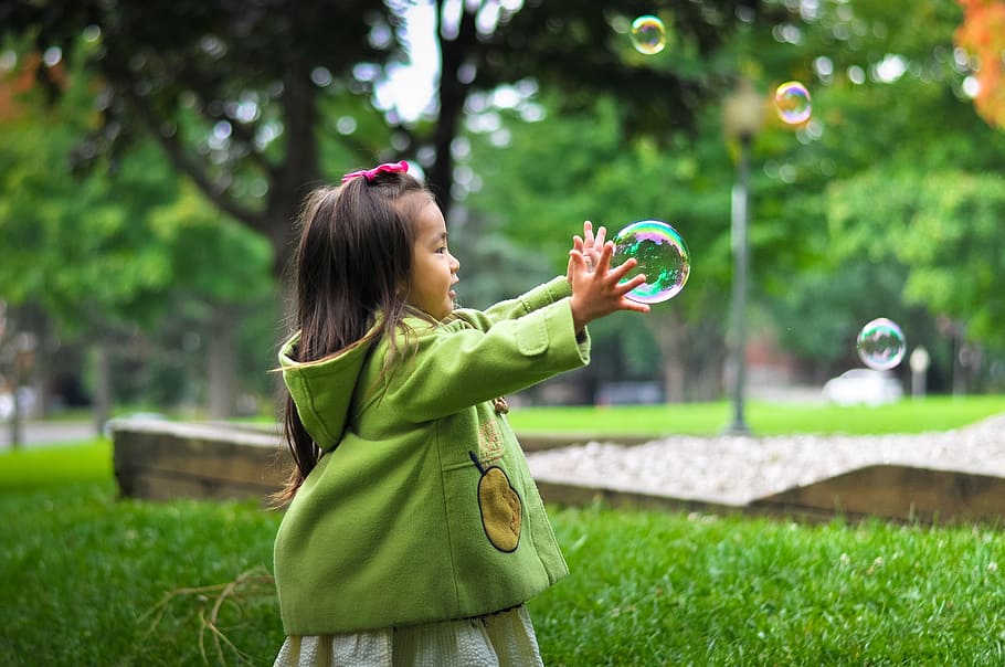 girl playing bubbles in green grass field, child, childhood, cute