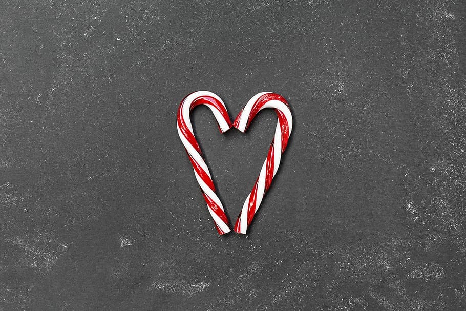 two red-and-white candy canes on gray surface, two candy canes making heart shape HD wallpaper