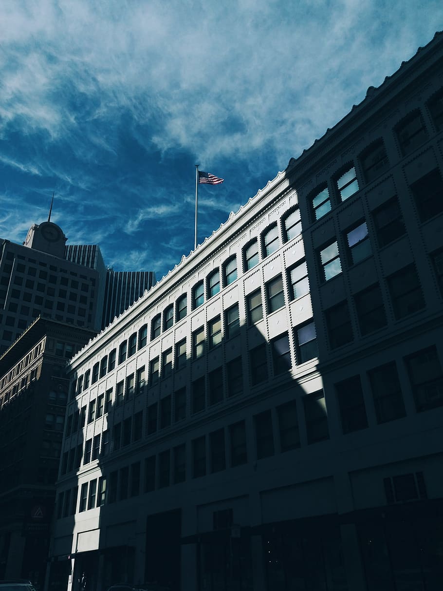 gray concrete wall building, low angle photo of building with flag on top HD wallpaper
