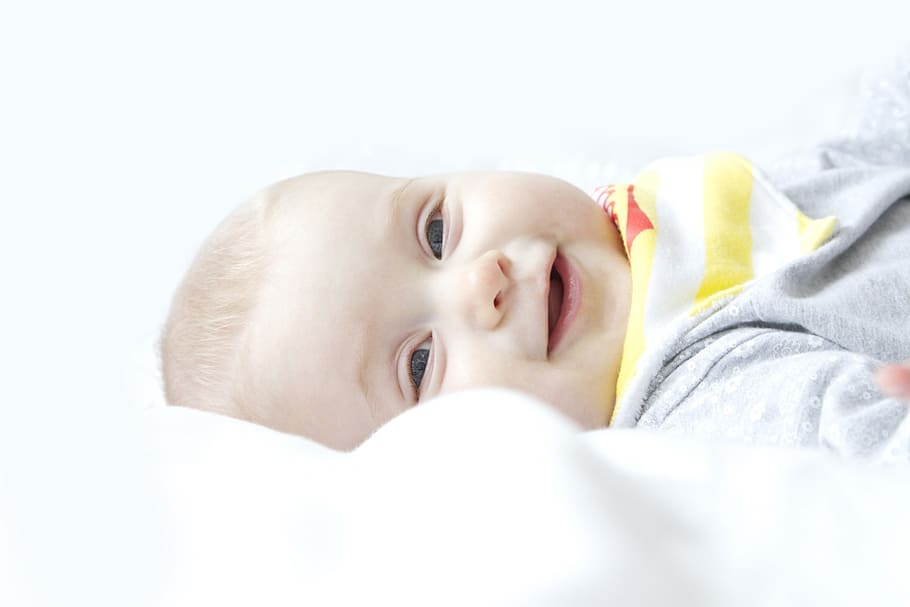 smiling baby lying on white textile, girl, boy, child, kid, face