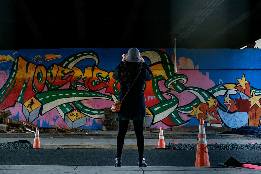 woman in blue coat standing in front of wall graffiti, woman standing in front of the wall, HD wallpaper