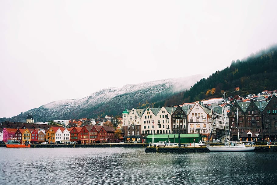 colorful townhouse beside body of water in Sweden, powerboat near village and mountains HD wallpaper