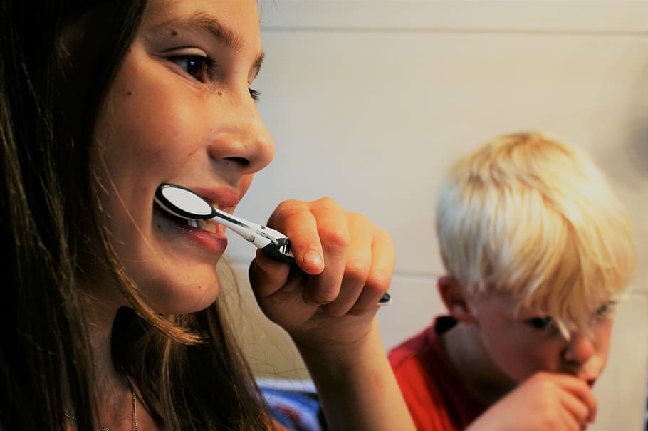 photo of girl and boy holding toothbrushes, brushing teeth, zahnarztpraxis