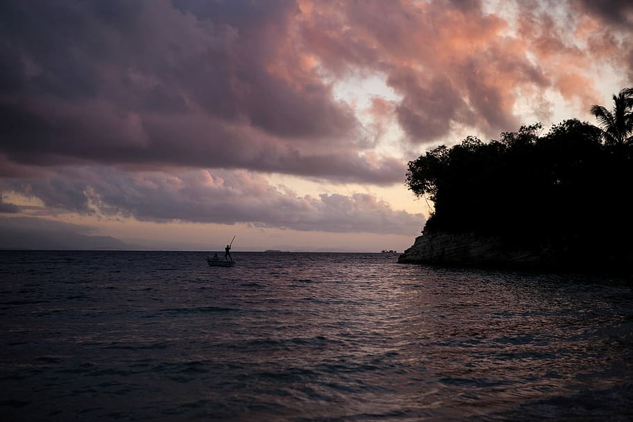 sail boat on body of water near island, cloudy sky over body of water HD wallpaper
