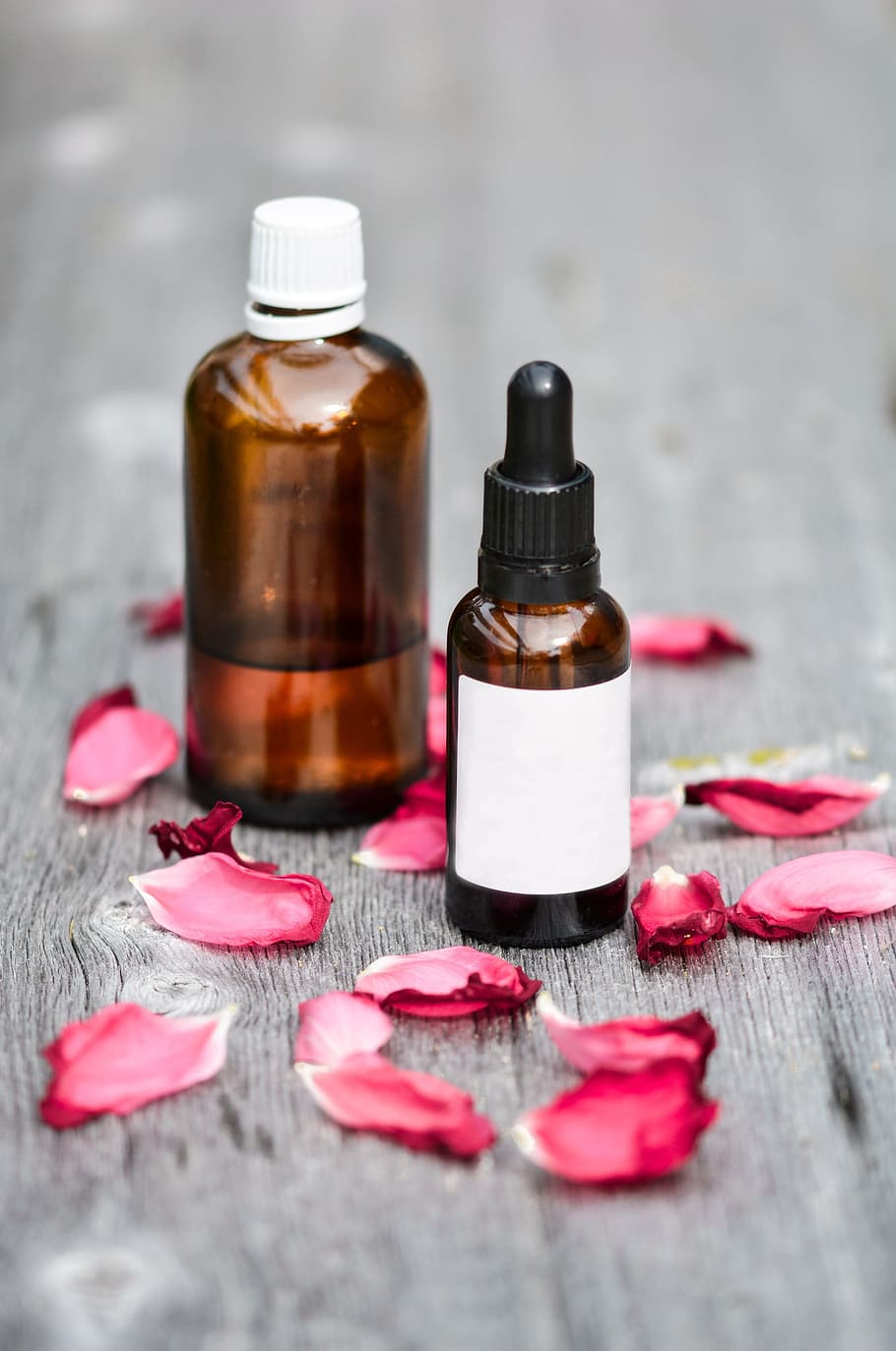 two amber glass bottles and red flower petals, essential oils HD wallpaper