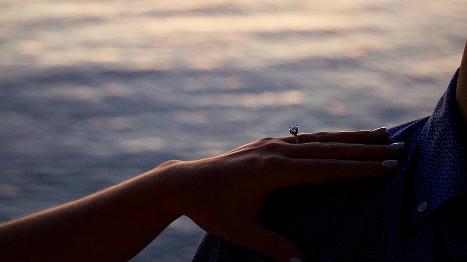woman holding man's right shoulder near body of water, hand HD wallpaper